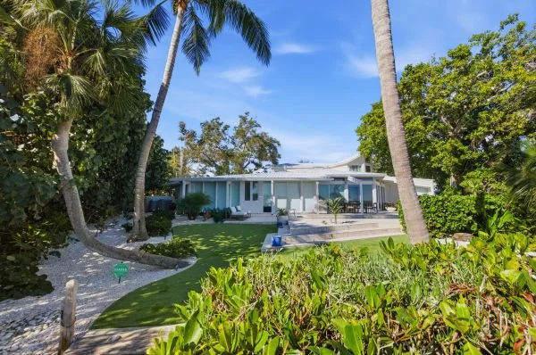 Tropical garden landscaping with palm trees surrounding a restored mid-century waterfront home in Siesta Key