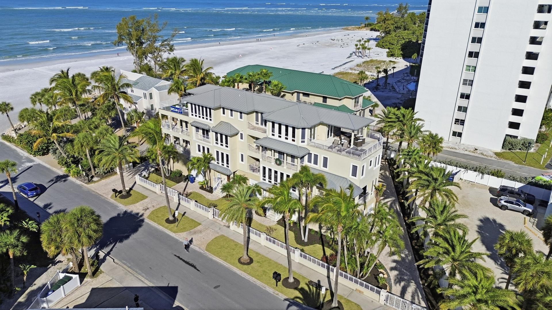 Aerial view of a coastal property with mature palms and professionally installed tropical landscaping in Sarasota, FL.